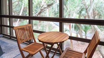 Una habitación con un amplio ventanal, dos sillas de madera y una pequeña mesa redonda.