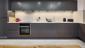 A modern kitchen with grey cabinets, a built-in oven, a sink, and a coffee maker. - Smart Northern Quarter Retreat (Manchester)