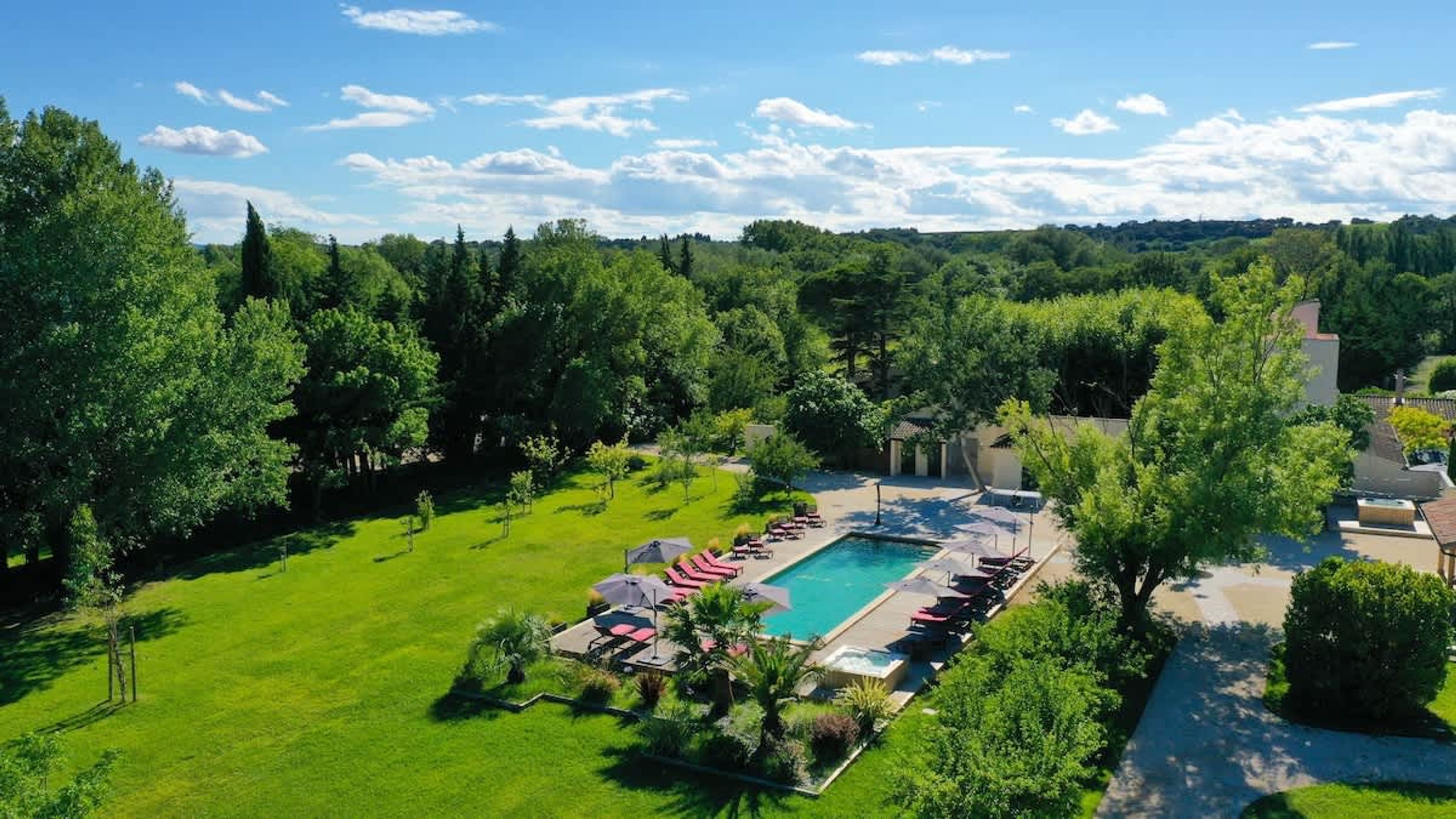 Vista aérea de um resort com piscina, espreguiçadeiras e vegetação exuberante.