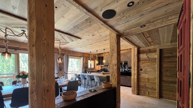 Un intérieur en bois comprenant un coin repas, une cuisine et une porte rouge.