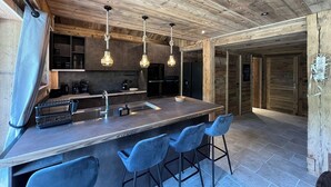 Une cuisine moderne avec un plafond en bois, des tabourets de bar et des luminaires suspendus.