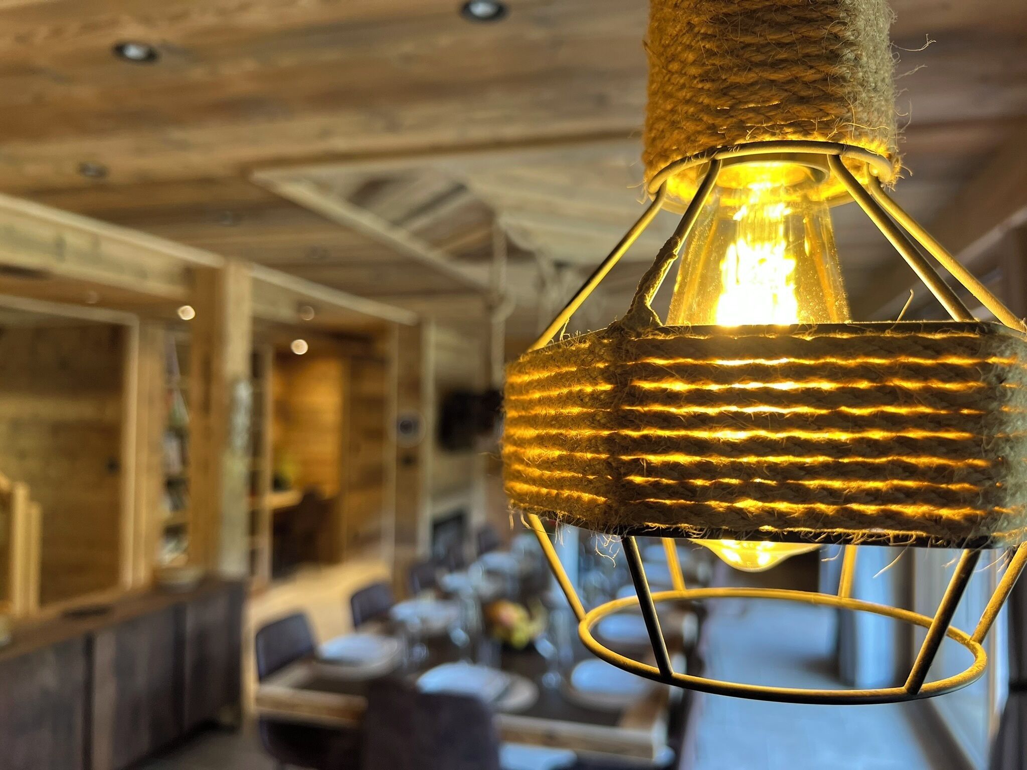 A hanging light fixture with a woven texture and a visible filament bulb.