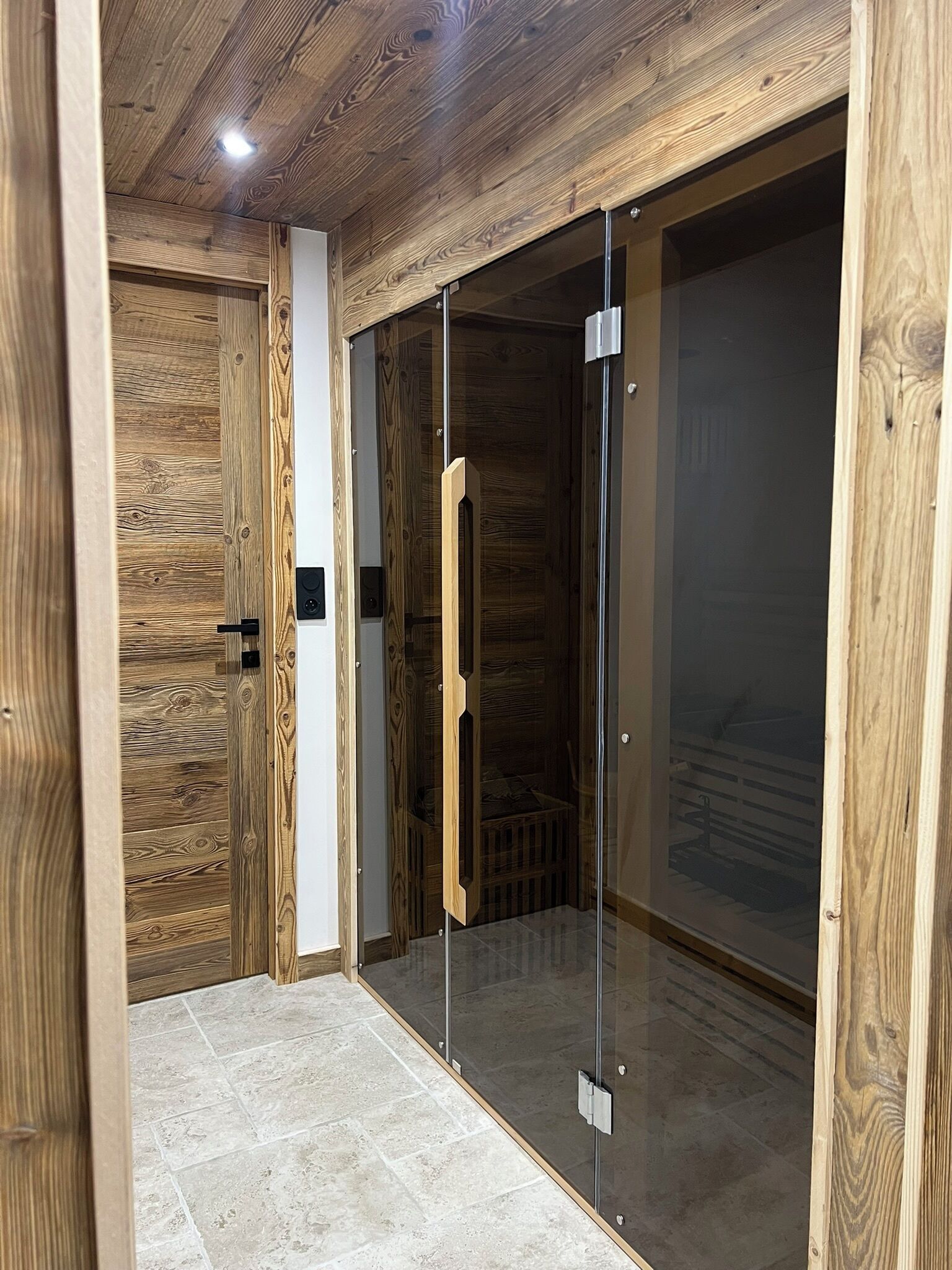 Un pasillo con paredes de madera y una puerta de cristal que da a una habitación.