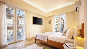 Une chambre d’hôtel avec un lit, une table de chevet avec une lampe, une télévision et une vue sur le balcon extérieur.