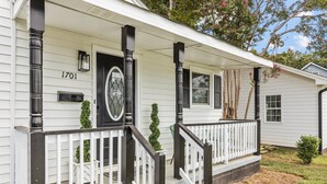 A white house with black trim, a front porch with a white railing, and a mailbox.