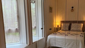 A bedroom with a large bed, a window, and a view of the outdoors. - Comfortable waterfront apartment with breathtaking views, nature break (Anthy-sur-Léman)
