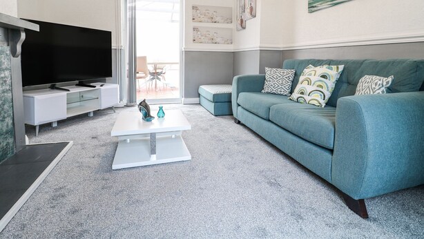 Una sala de estar moderna con un televisor de pantalla plana, un sofá verde azulado y una mesa de centro.