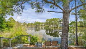 A tranquil lakeside setting with a wooden dock, a bench, and a sign indicating a caution area. - Beachside Daze 812-Coastal Comfort-Sleeps 6 (Santa Rosa Beach)