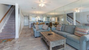 A spacious living room with a grey sofa, a wooden coffee table, and a staircase leading to another level.