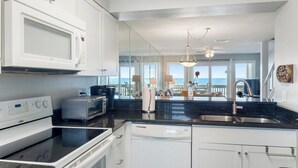 A modern kitchen with white cabinets, a black countertop, a microwave, a toaster, and a dishwasher.
