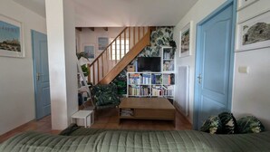 A bedroom with a bed, a bookshelf, a TV, and a staircase. - Villa T5 Swimming pool with view of Lac du Salagou (Liausson)