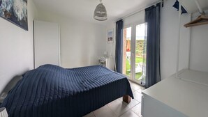 A bedroom with a bed, a desk, a chair, a wardrobe, and a view of the outdoors through a sliding door. - Villa T5 Swimming pool with view of Lac du Salagou (Liausson)