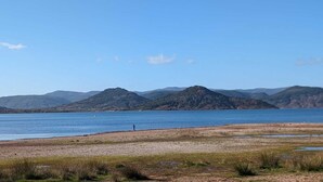 A natural landscape with a lake, mountains, and a person walking on the shore. - Villa T5 Swimming pool with view of Lac du Salagou (Liausson)