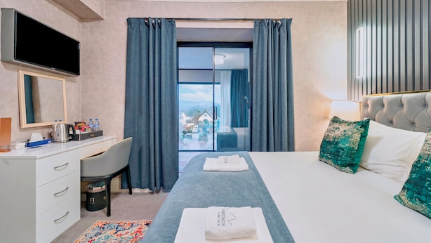 Habitación de hotel con cama, escritorio, televisión y vistas a través de un ventanal.