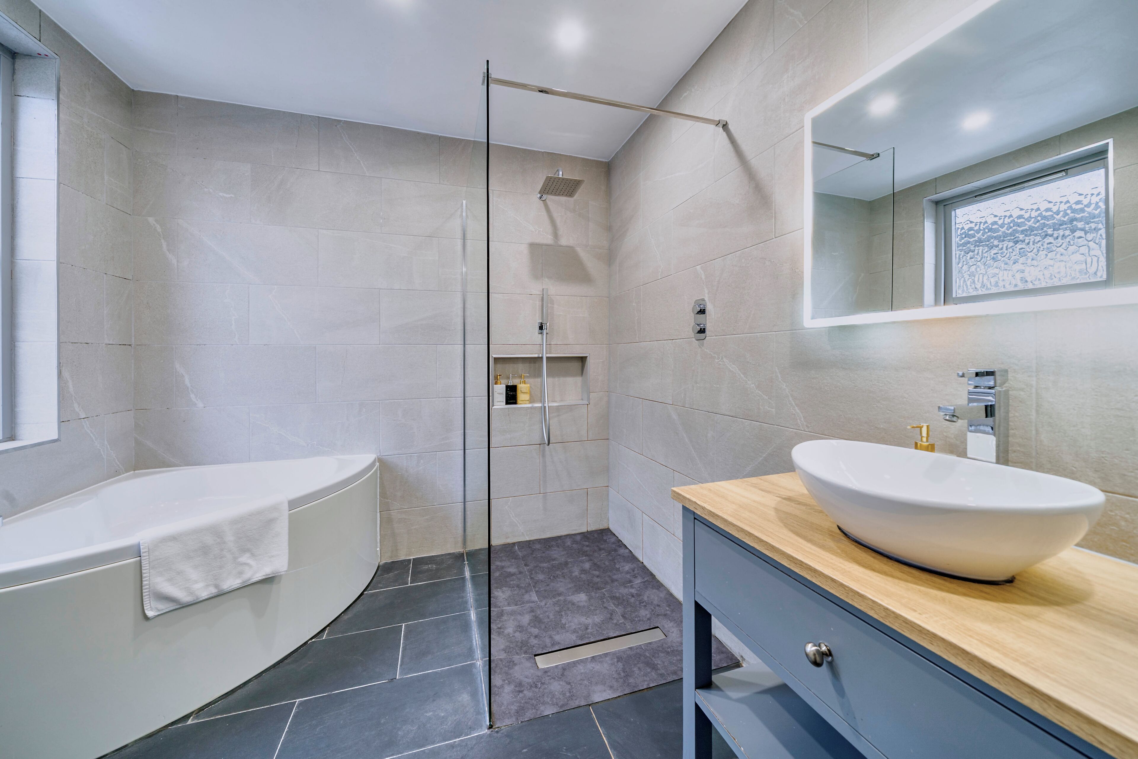 A modern bathroom with a bathtub, a glass-enclosed shower, and a vanity with a sink.
