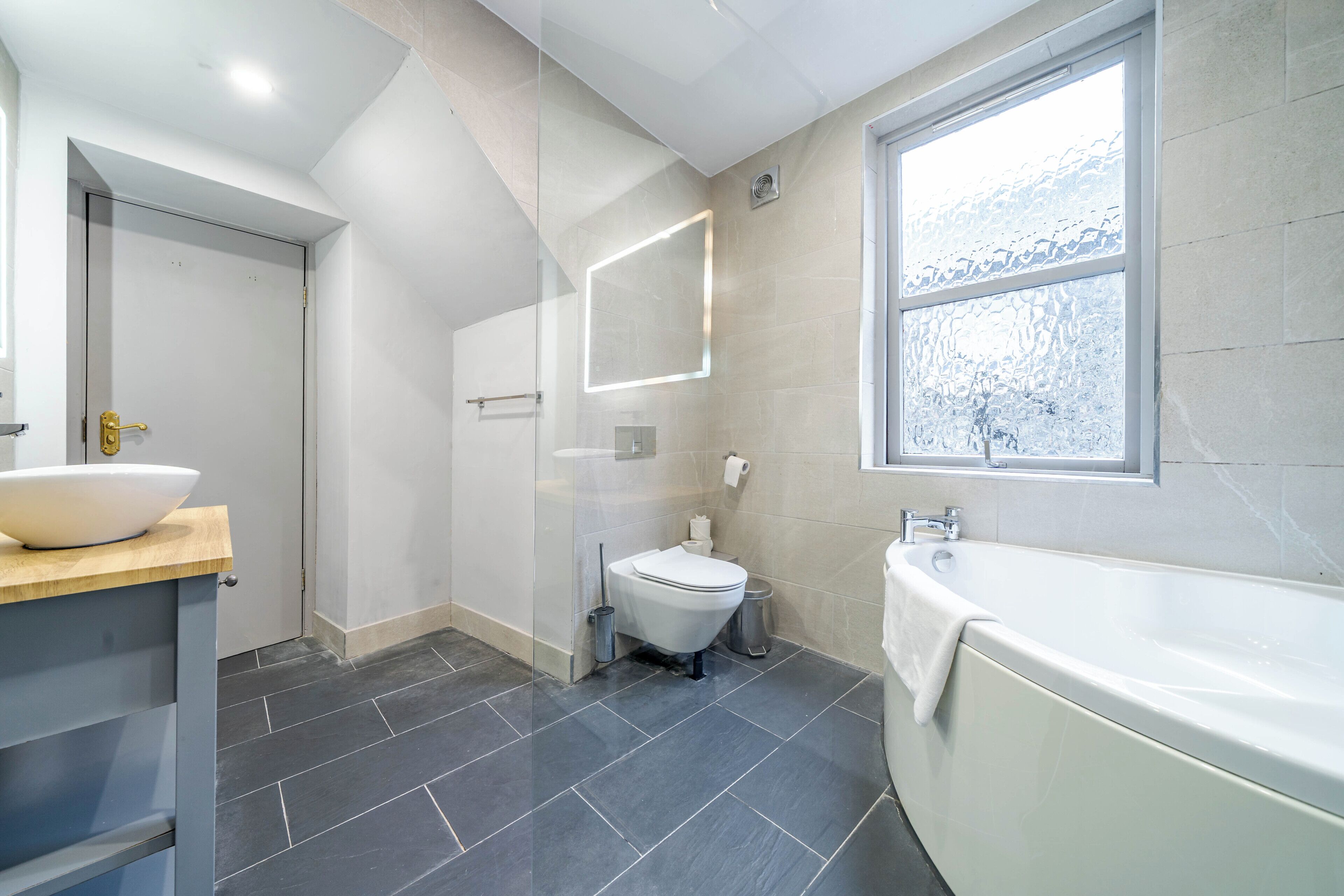 Un baño moderno con una bañera grande, un inodoro y un lavabo.