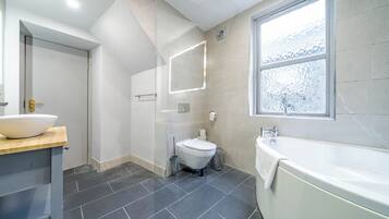 Un baño moderno con una bañera grande, un inodoro y un lavabo.
