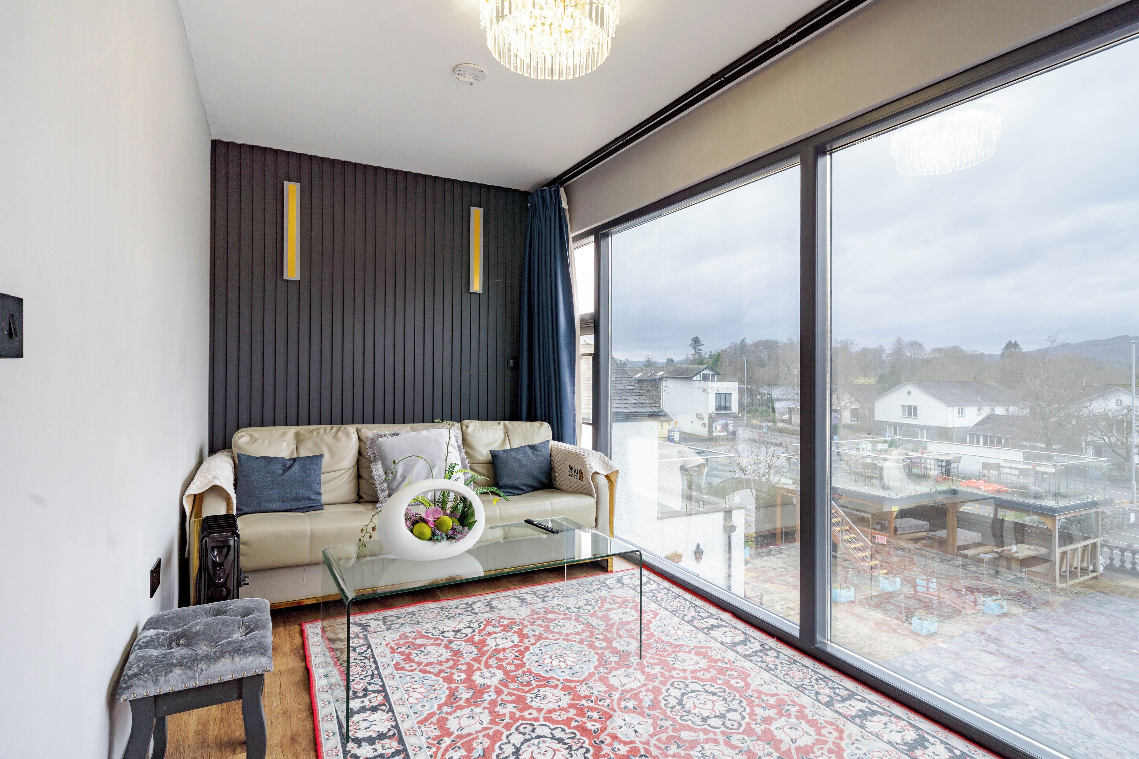 Un salon moderne avec un canapé, une table basse en verre et une grande fenêtre donnant sur la ville.