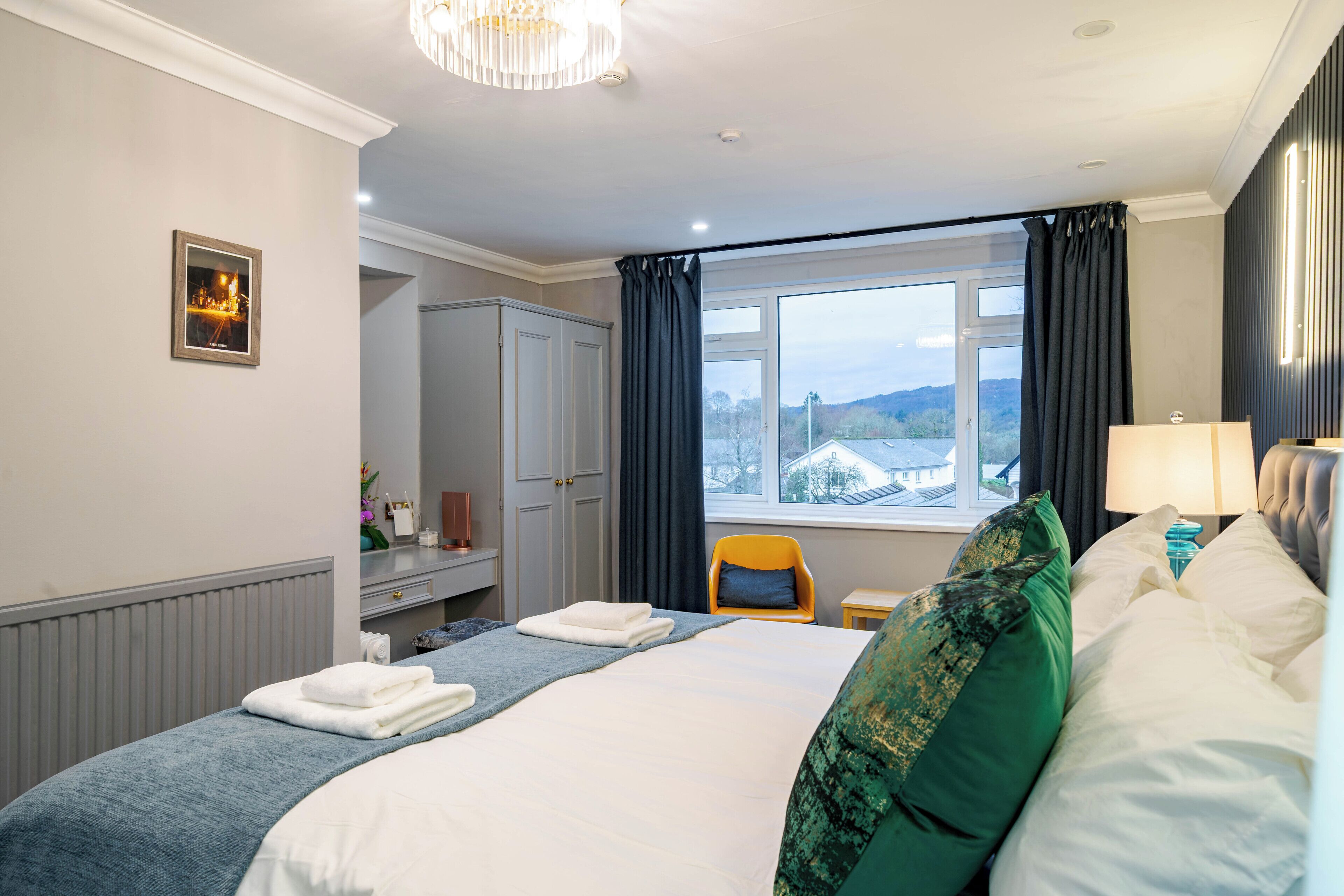 Een hotelkamer met een bed, een stoel, een bureau en een raam met gordijnen.
