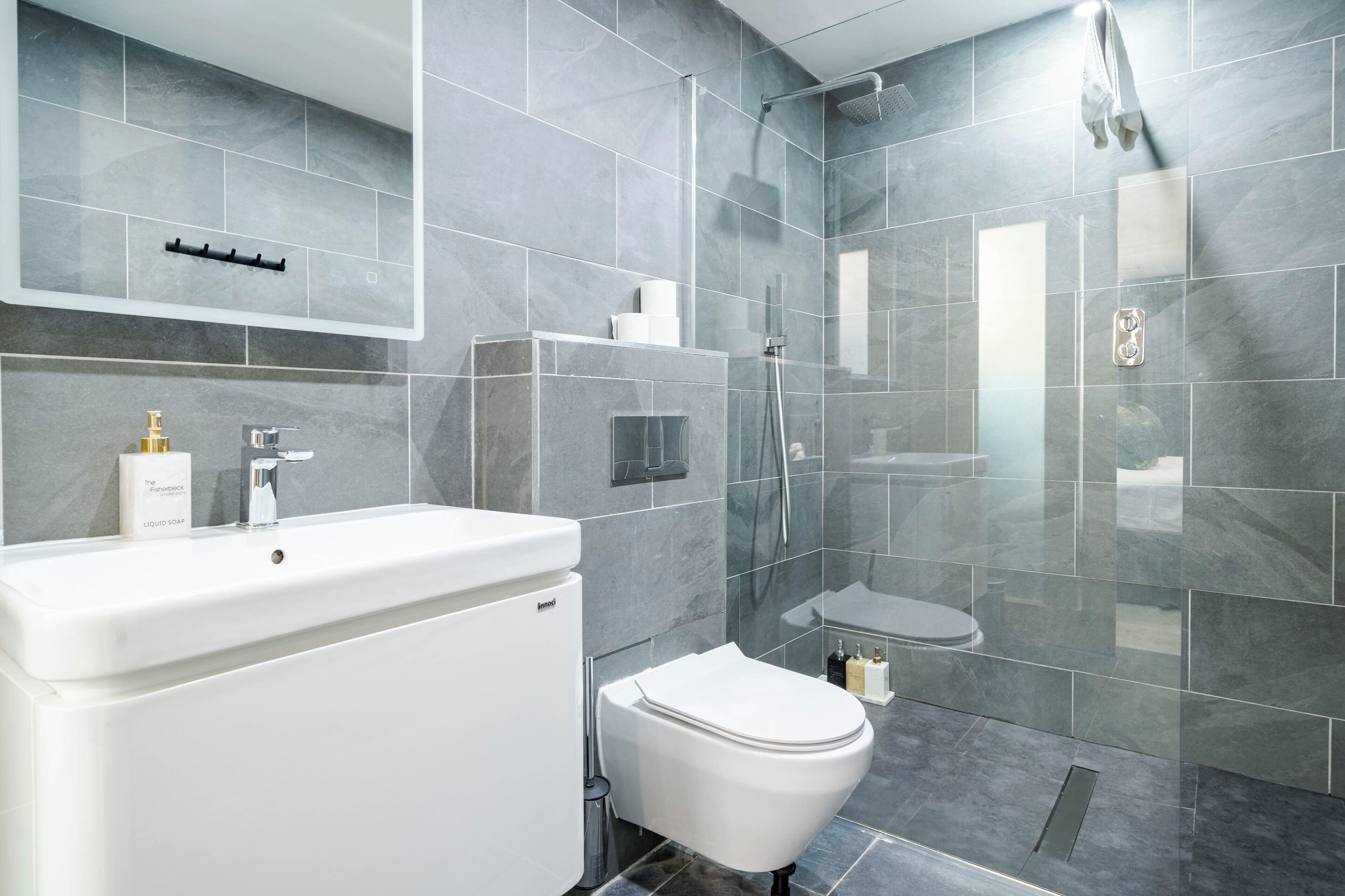 Une salle de bain moderne avec un lavabo, des toilettes et une douche, le tout de couleur blanche.