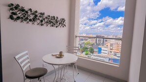 A balcony with a white table and chairs, a decorative plant wall, and a city view through a large window. - Elite Residence  (Nairobi)