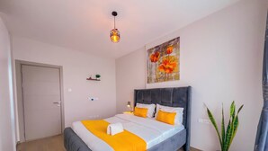 A bedroom with a bed, a bedside lamp, a potted plant, and a painting on the wall. - Elite Residence  (Nairobi)