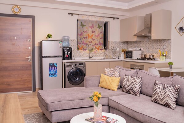 A modern kitchen with a washing machine, a coffee maker, and a microwave.