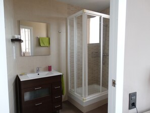 Uma casa de banho moderna com cabine de duche em vidro, toucador com espelho e porta-toalhas.