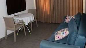 A living room with a blue sofa, a TV, and a table with chairs. - Nature Maris Apart (Marmaris)