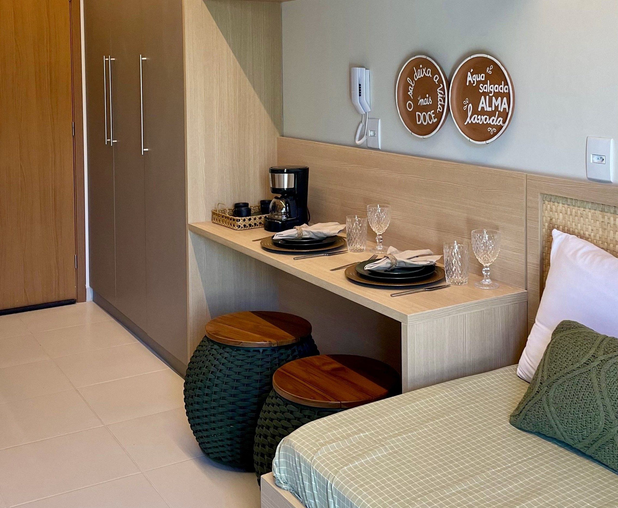 A modern bedroom with a bed, bedside table, and a small kitchenette area.