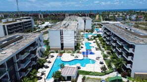 A resort with multiple buildings, a central swimming pool, and a view of the ocean. - Makia Beach - Porto de Galinhas (Ipojuca)