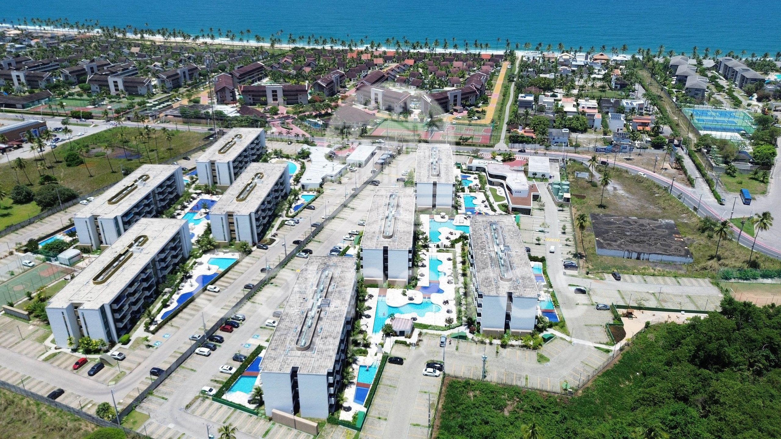 Un gran complejo hotelero con varias edificaciones, piscinas y vista a la playa.