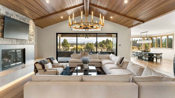 A spacious living room with a large sectional sofa, a fireplace, and a large window offering a view of the outdoors.