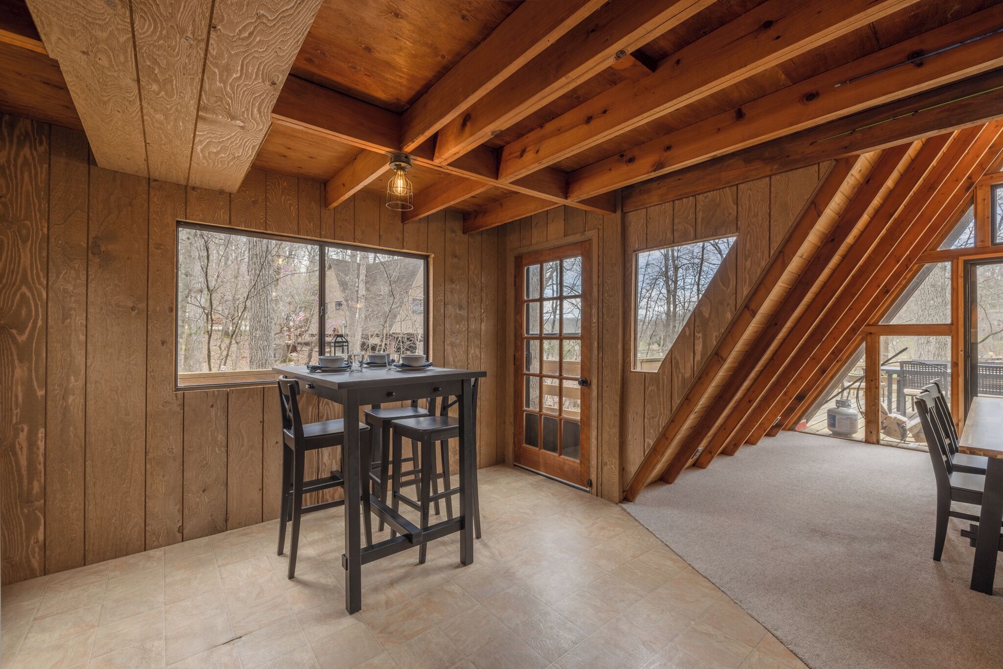 Interior de madera con una mesa de comedor y sillas, ventanas amplias y techo inclinado.
