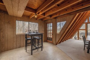 Interior de madera con una mesa de comedor y sillas, ventanas amplias y techo inclinado.