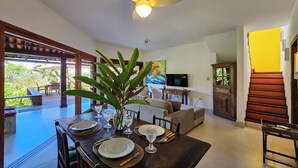 A dining area with a table set for four, a ceiling fan, and a view of the outdoors. - Casa Maritacas (Sao Sebastiao)