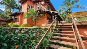 A two-story house with a wooden staircase leading to a balcony. - Casa Maritacas (Sao Sebastiao)