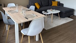 A modern living space with a dining area, grey sofa, and a ceiling light fixture. - T4 Bright and comfortable - Secure residence (Déville-lès-Rouen)
