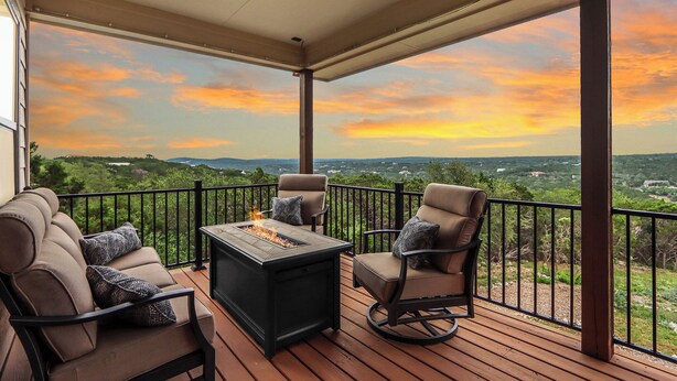 Una terraza exterior cubierta con una mesa para fuego, dos sofás y dos sillones, con vistas a un paisaje pintoresco.