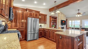 Una cocina moderna con armarios de madera, electrodomésticos de acero inoxidable, encimeras de granito y una pared de acento de piedra.