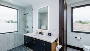 Ein modernes Badezimmer mit einem großen Spiegel, einem Waschbecken und einer Toilette.