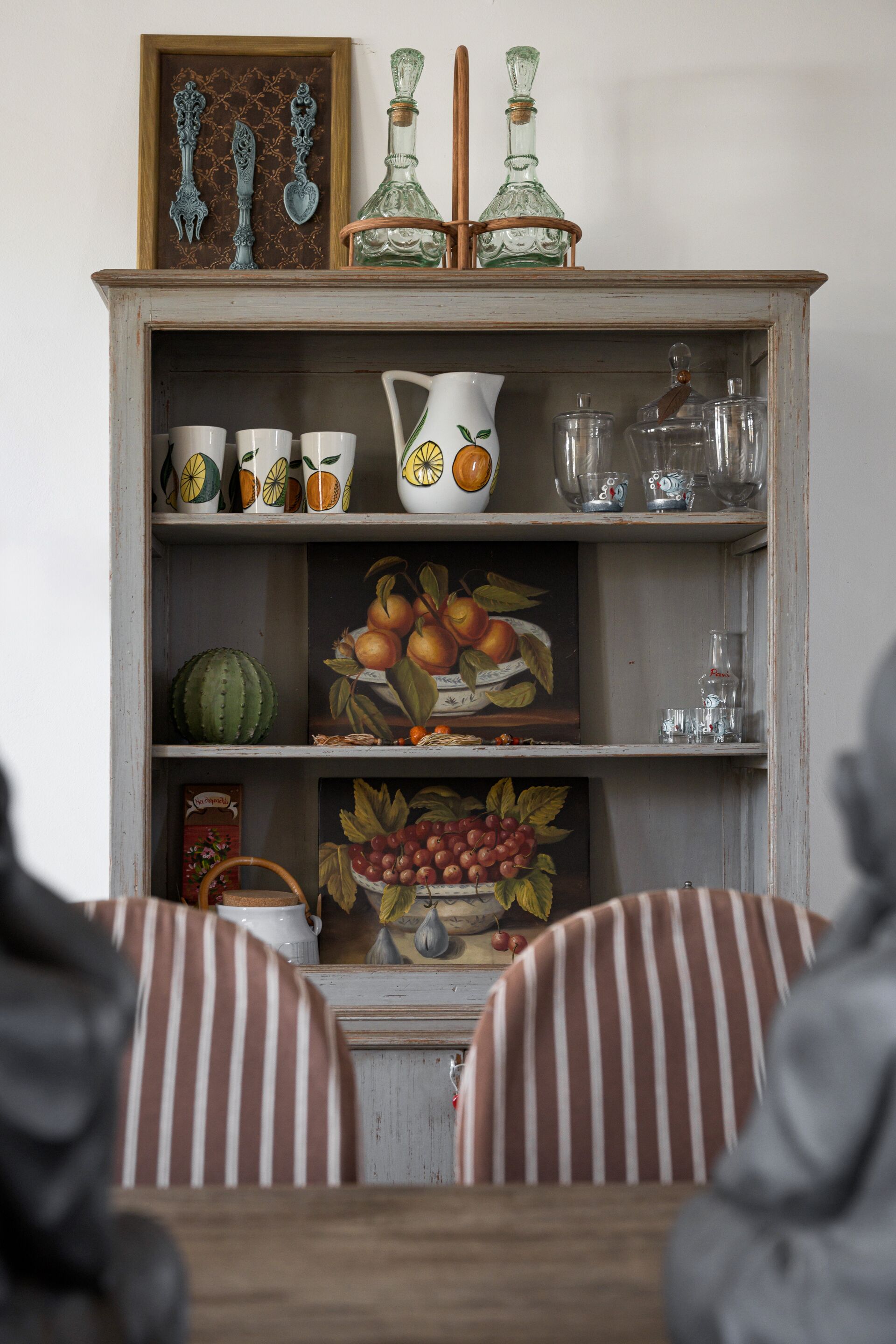 Un meuble en bois, doté d’étagères où sont exposés divers ustensiles de cuisine et objets décoratifs.