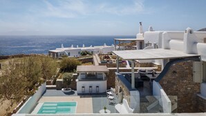 Een landhuis aan de kust met een zwembad, terras en uitzicht op zee.