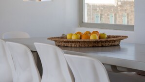 Een eetgedeelte met een tafel, stoelen en een mand met fruit.