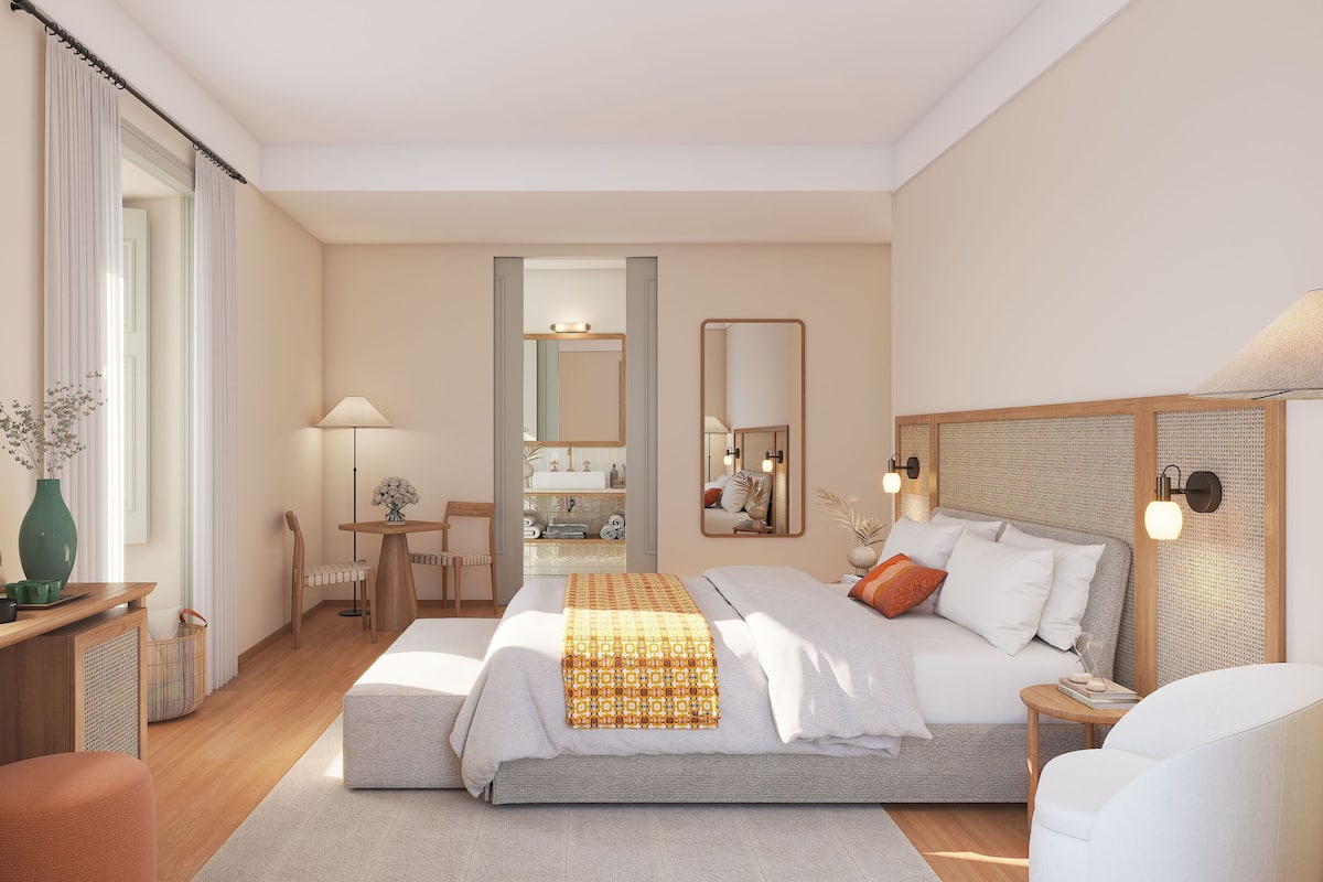 Habitación de hotel moderna con cama, mesita de noche, lámpara y vistas al baño.
