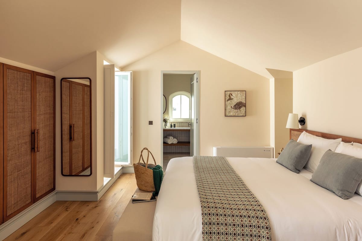 Un dormitorio con una cama grande, un armario, un espejo y vistas al baño.