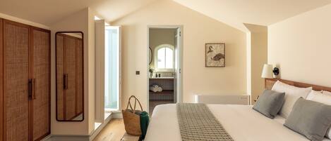 A bedroom with a large bed, a wardrobe, a mirror, and a view of a bathroom.