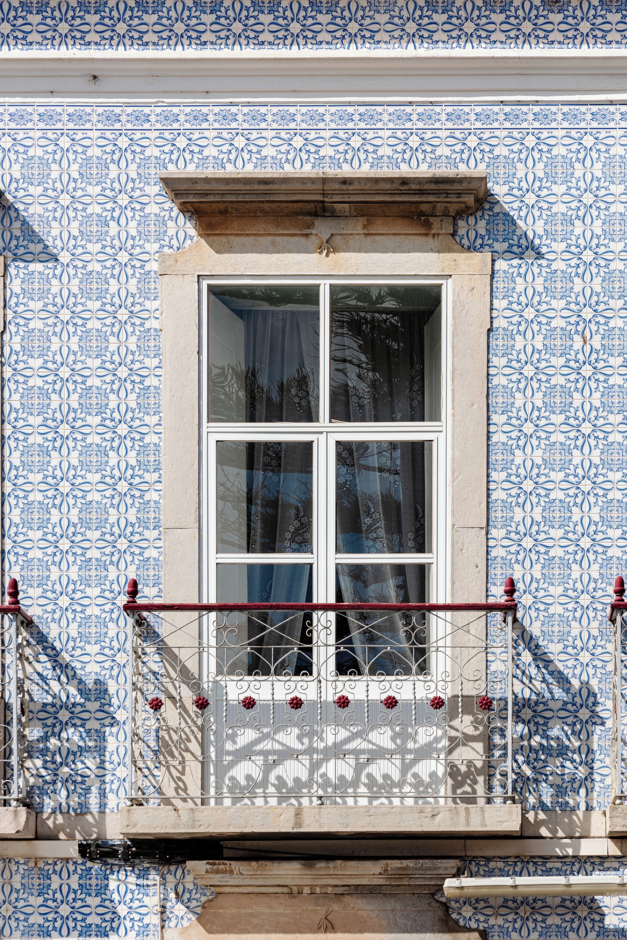 A window with a white frame and a balcony with a metal railing.