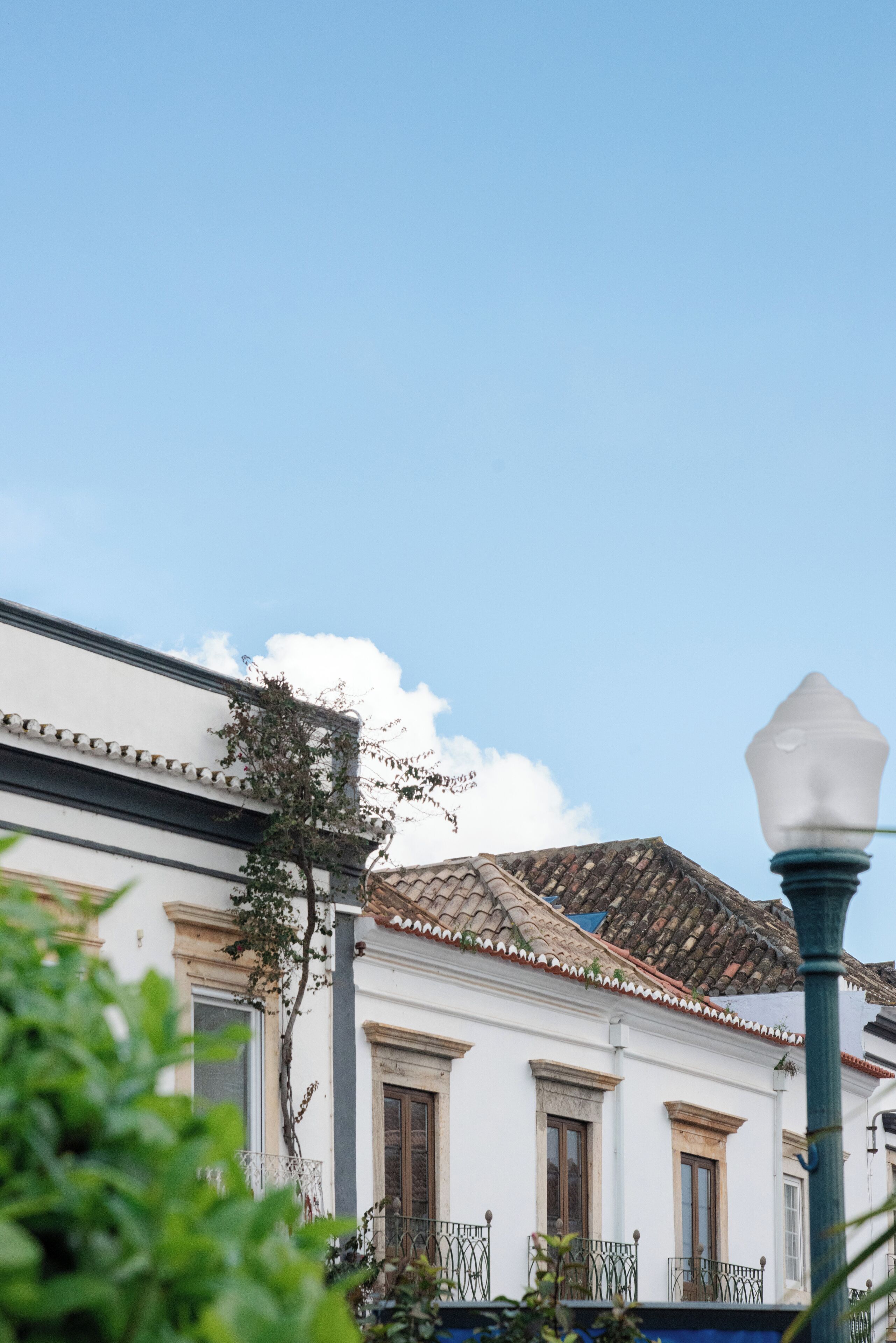 A traditional building with a tiled roof and white walls, featuring a balcony with a wrought iron railing.