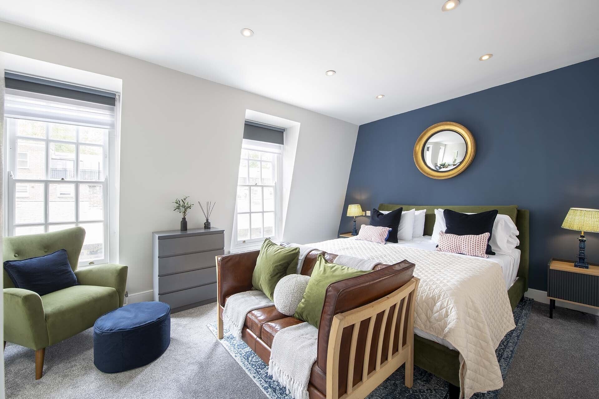 A bedroom with a bed, a chair, a dresser, and a lamp.